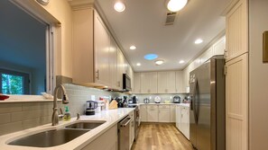 A modern kitchen with white cabinets, stainless steel appliances, and a wooden floor.