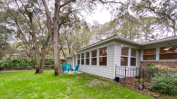 A single-story house with a covered porch, surrounded by a well-maintained lawn and trees.