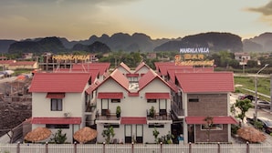 A hotel with a red roof, white walls, and a sign for 'Mandalaville Bar Restaurant'. - Tam Coc Mandala Villa & Homestay  (Nam Hoa Lu)