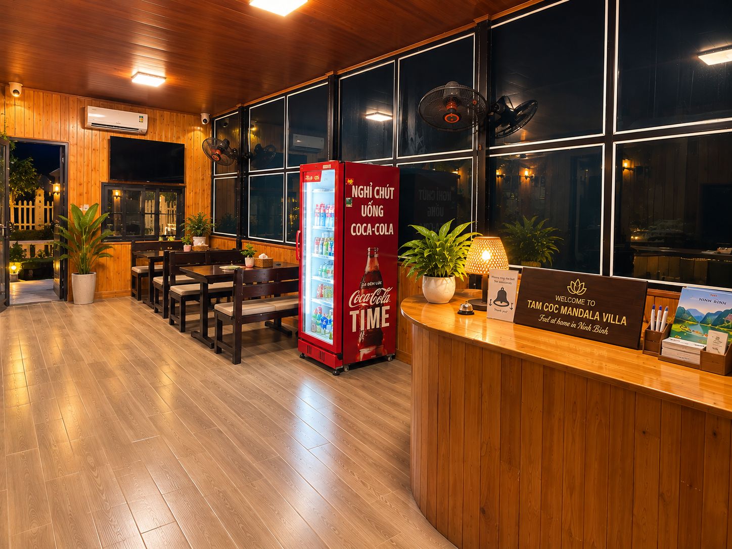 Een receptiegedeelte met een Coca-Cola koelkast, houten meubels en een bord met een welkomstboodschap voor het gebied Ninh Binh.