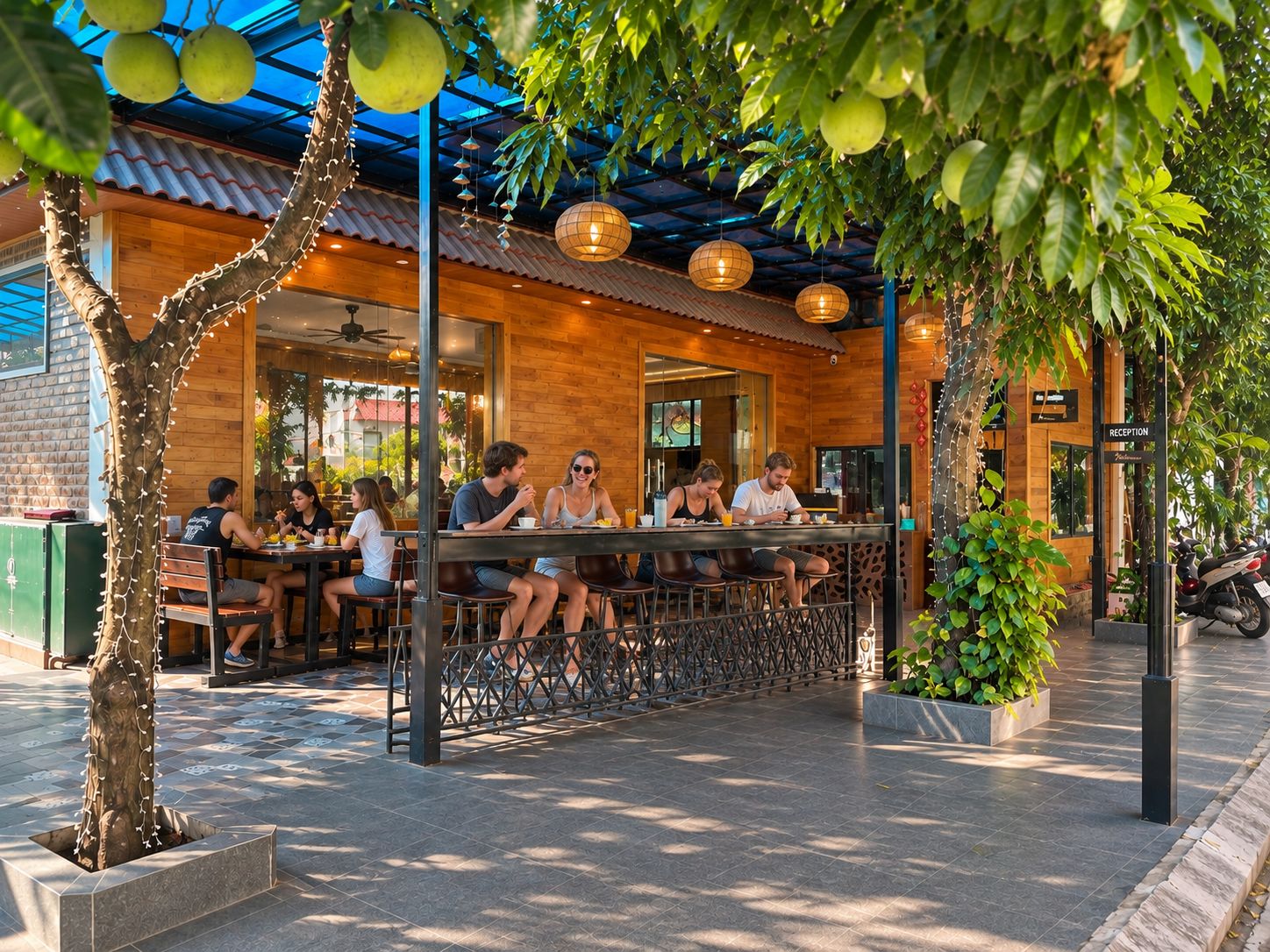 An outdoor seating area with tables and chairs, surrounded by greenery and a building with a wooden facade.