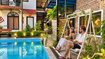 A poolside area with a swing chair, a bench, and a small pool.