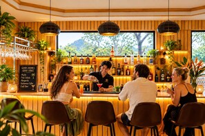 Un bar con paneles de madera, una pizarra con la carta y un camarero sirviendo bebidas.