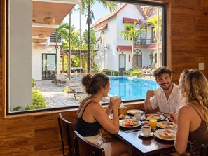 Un comedor con vistas a una piscina y un edificio con tejados rojos.