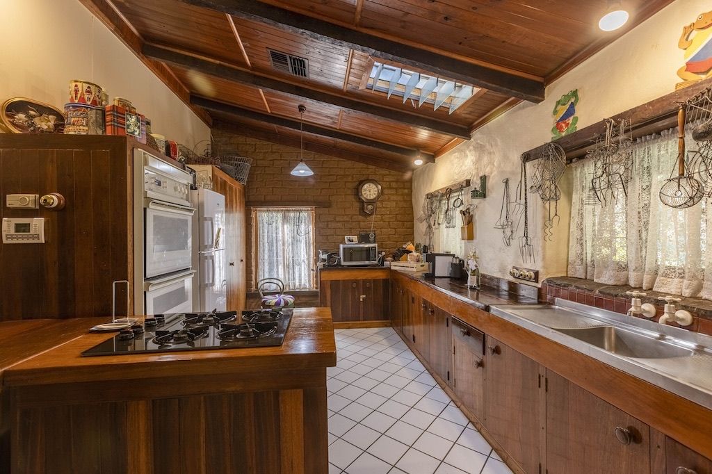A kitchen with wooden cabinets, a gas stove, a refrigerator, and a sink.