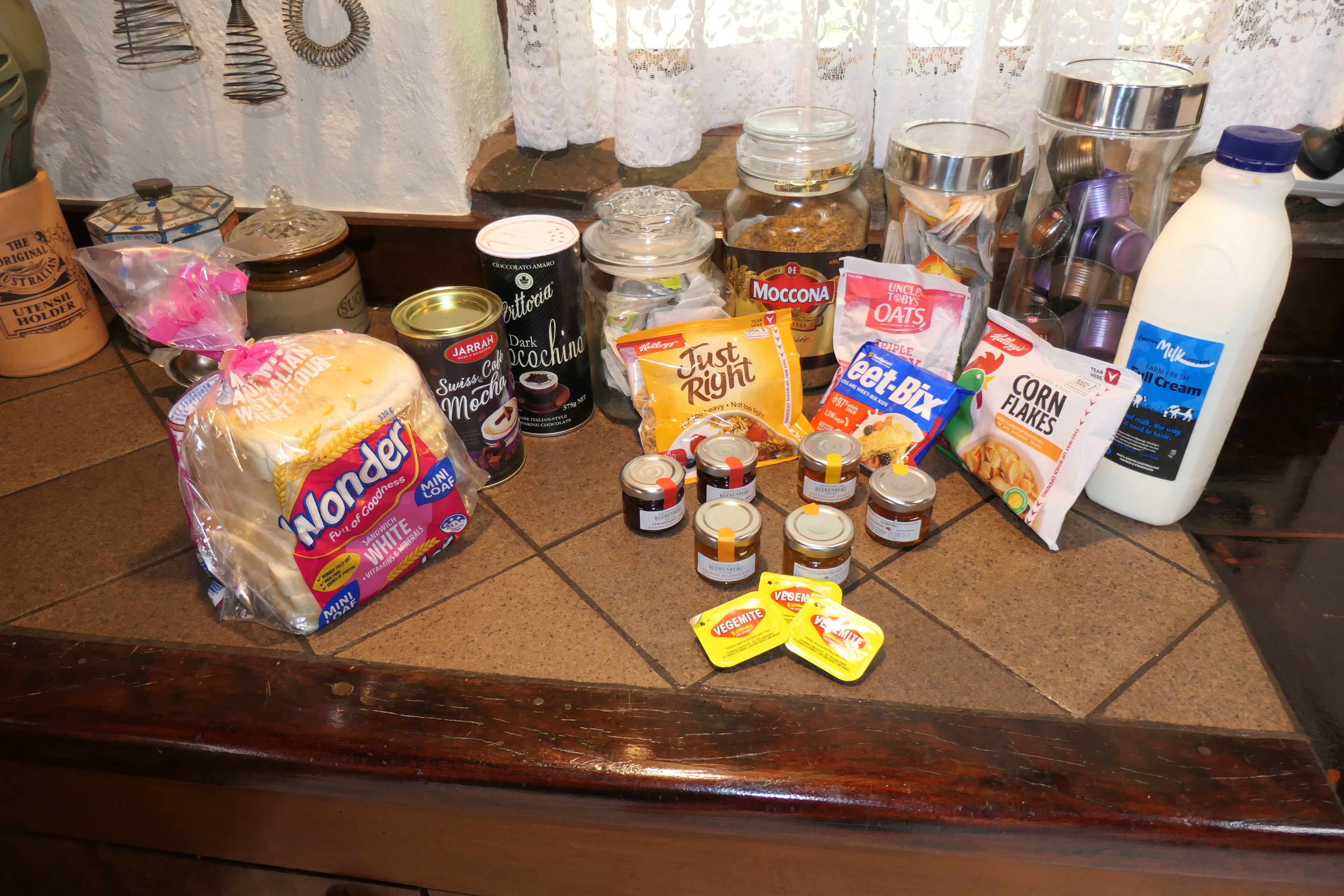 A kitchen counter with various food items and containers, including jars, a milk bottle, and packaged snacks.