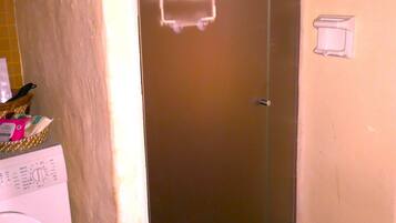 A compact room with a washing machine, a door with a handle, and a tiled floor.