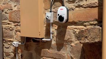 A utility box is mounted on a stone wall, connected to an electrical box and security camera.