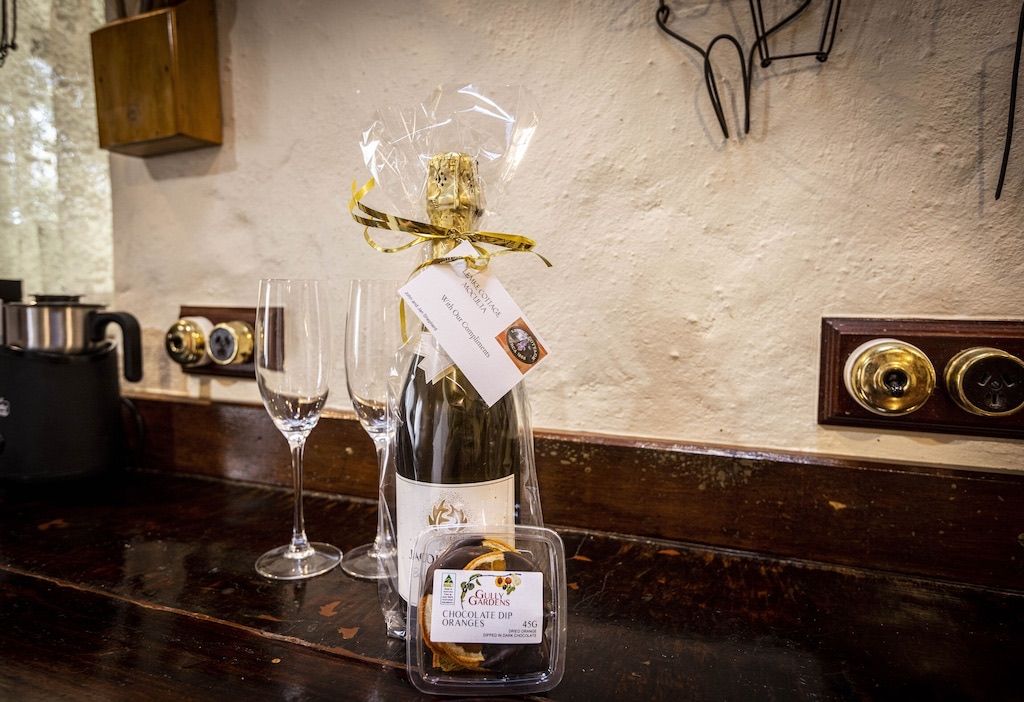 Uma garrafa de vinho com etiqueta e uma caixa de bombons de laranja sobre um balcão de bar.