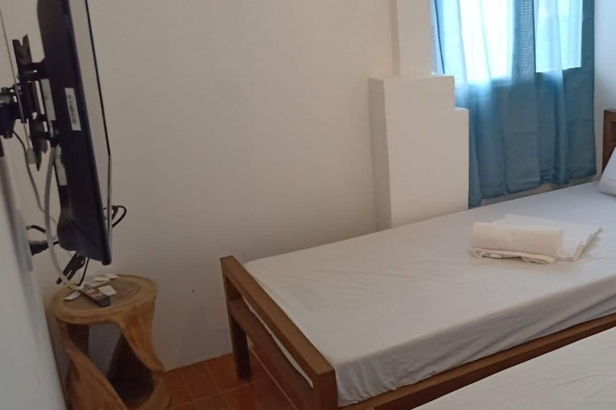 A small, single-bed room with a wooden frame, white bedding, and a small wooden stool with a phone on it.