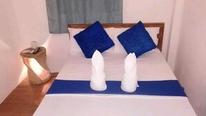 A bed with a blue bedspread and two white towels arranged to resemble a pair of legs.