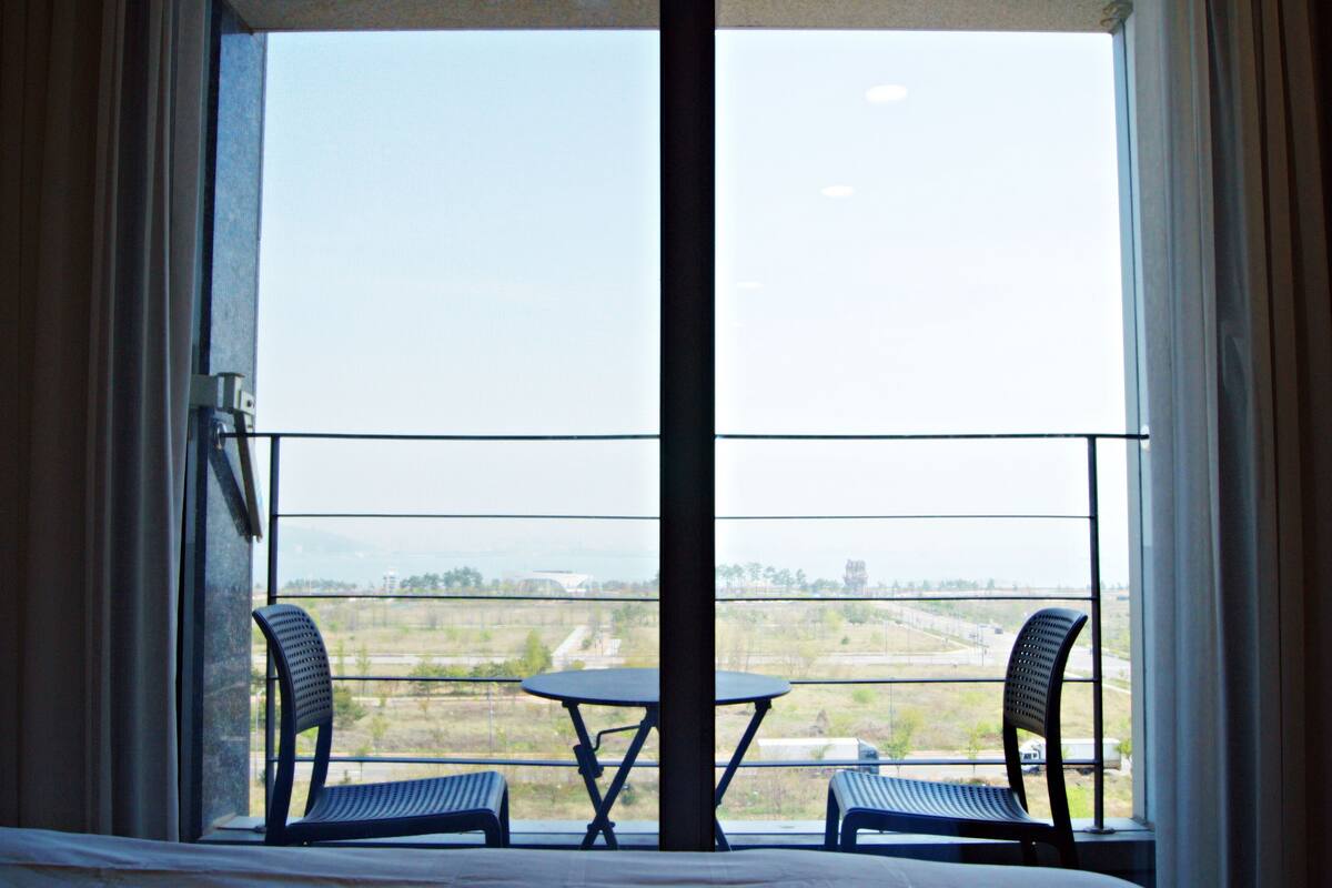 A balcony with two chairs and a table, offering a view of a distant landscape.
