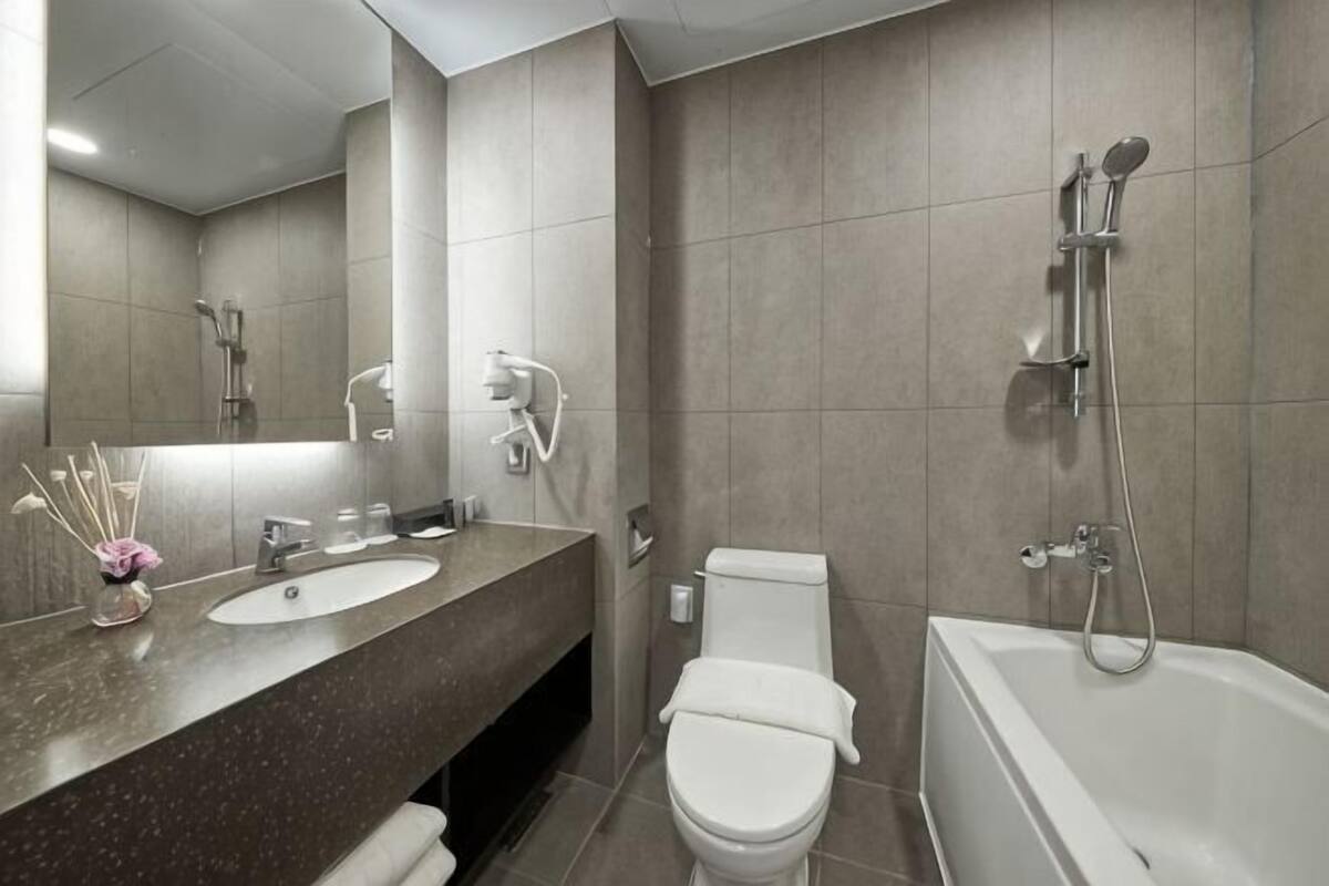 A modern bathroom with a marble sink, a toilet, and a bathtub.