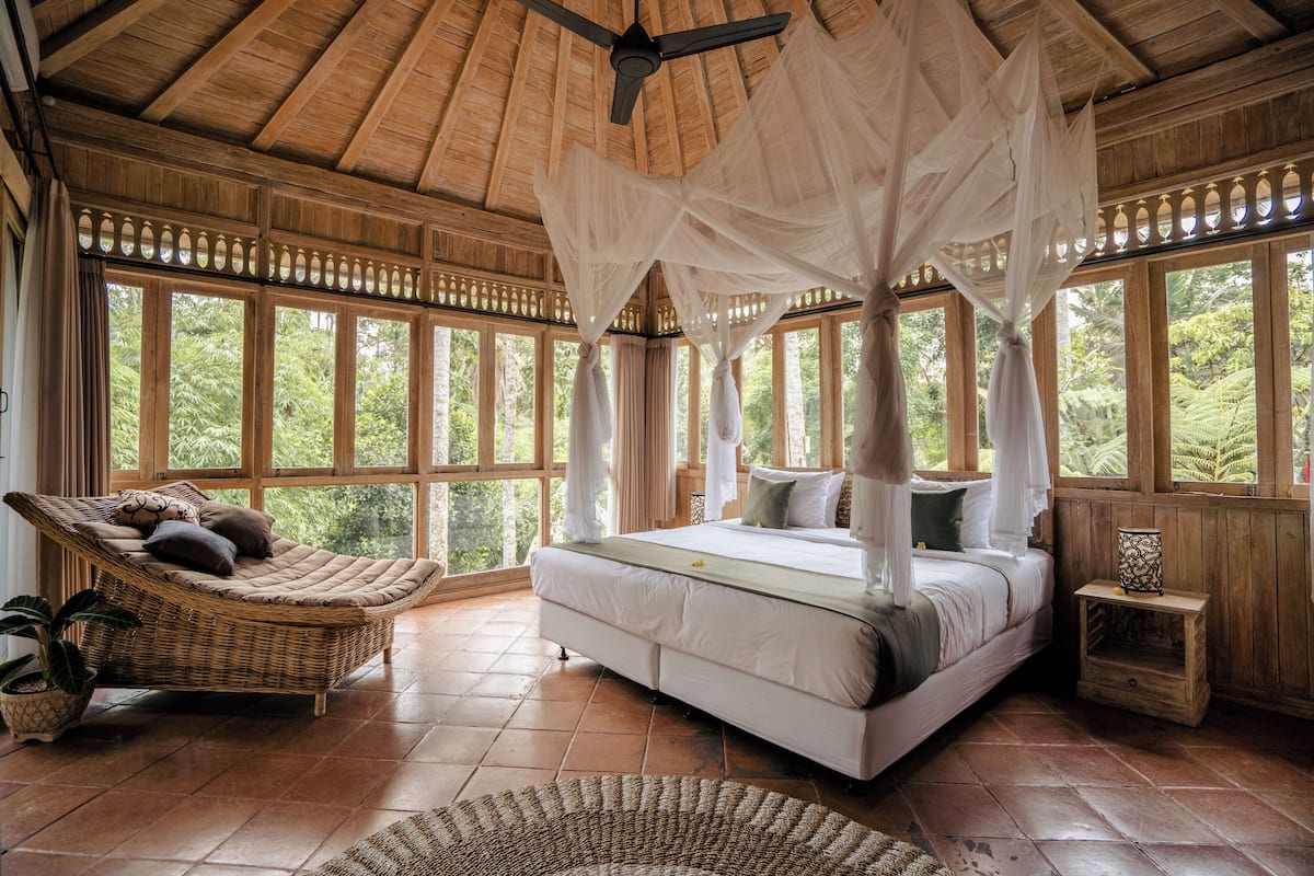Um quarto espaçoso com uma cama grande, uma cadeira suspensa e uma pequena mesa de cabeceira.