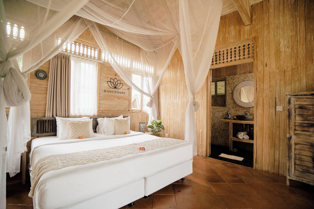 Quarto amplo com uma cama grande, paredes de madeira e um dossel.