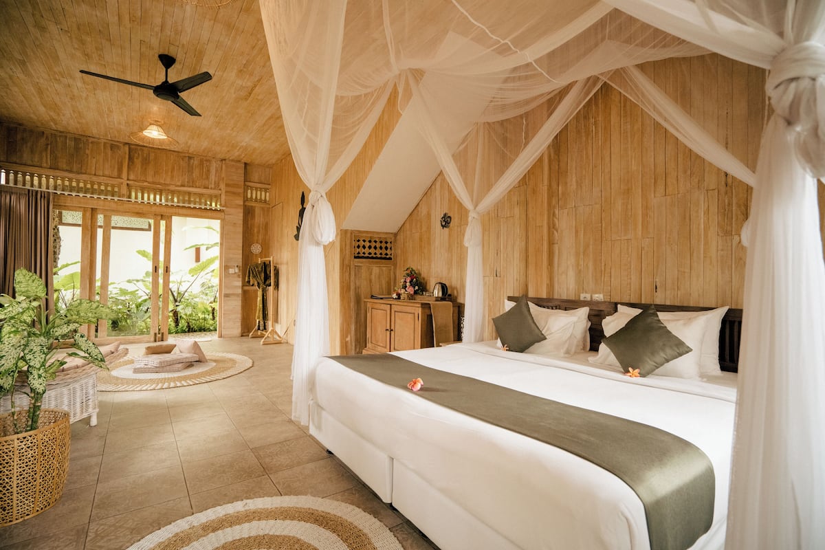 Um quarto espaçoso com uma cama grande, um ventilador de teto e vista para o exterior.