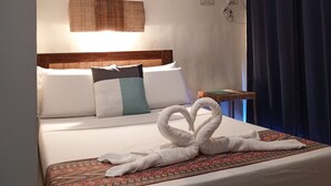 A hotel room with a bed, pillows, a wall-mounted air conditioner, a bedside table, and a curtain. - Casa Montemar B&B (Coron)