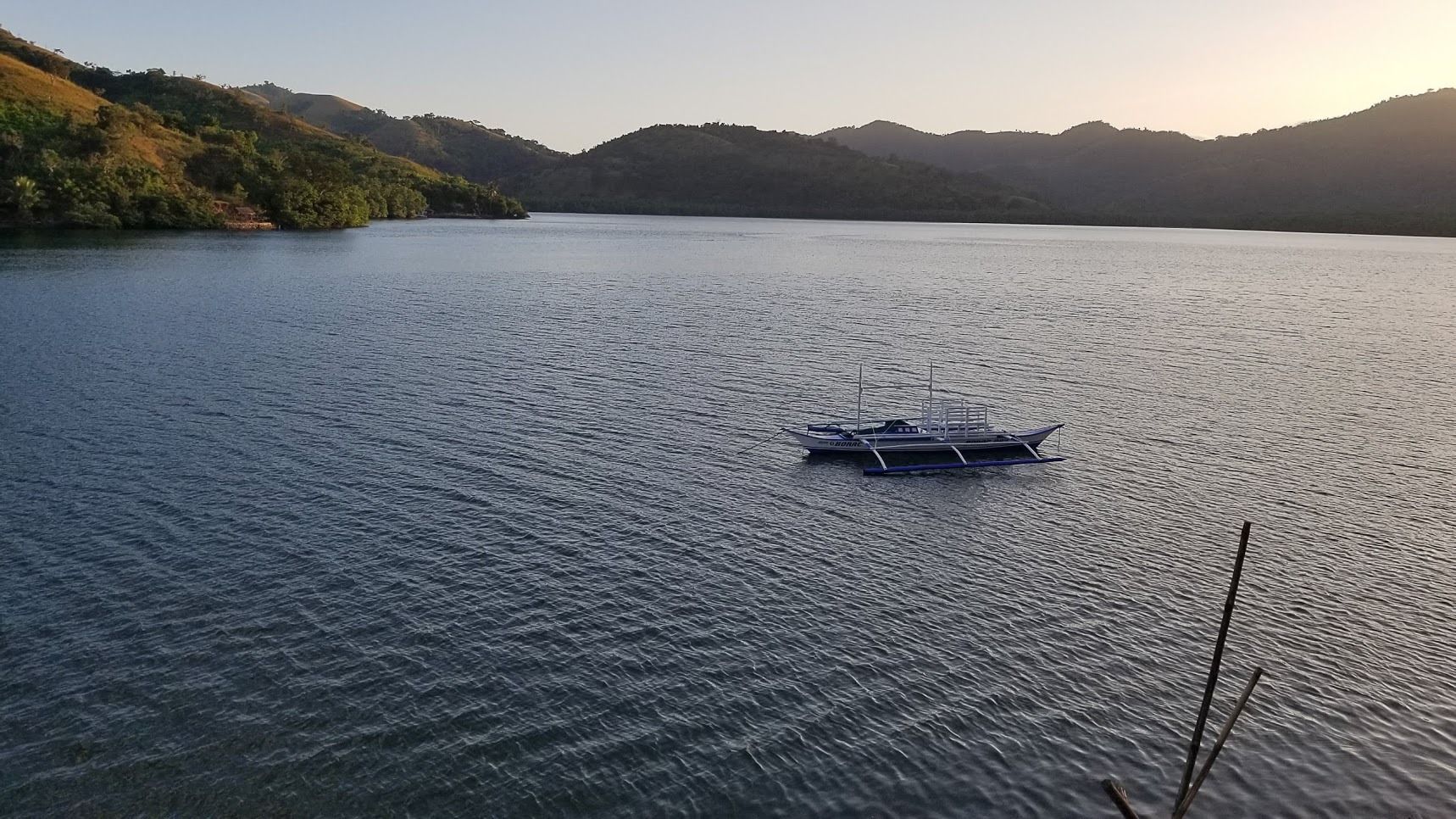 Un bote en un lago tranquilo rodeado de colinas.