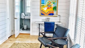 A room with a large window, a chandelier, a painting, and a seating area with chairs. - Crocker Inn (Vineyard Haven)