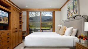 A bedroom with a large bed, wooden cabinets, a television, and a balcony with a mountain view. - Villas at Snowmass Club - 1423 ~ Snowmass Club Access ~ (Snowmass Village)