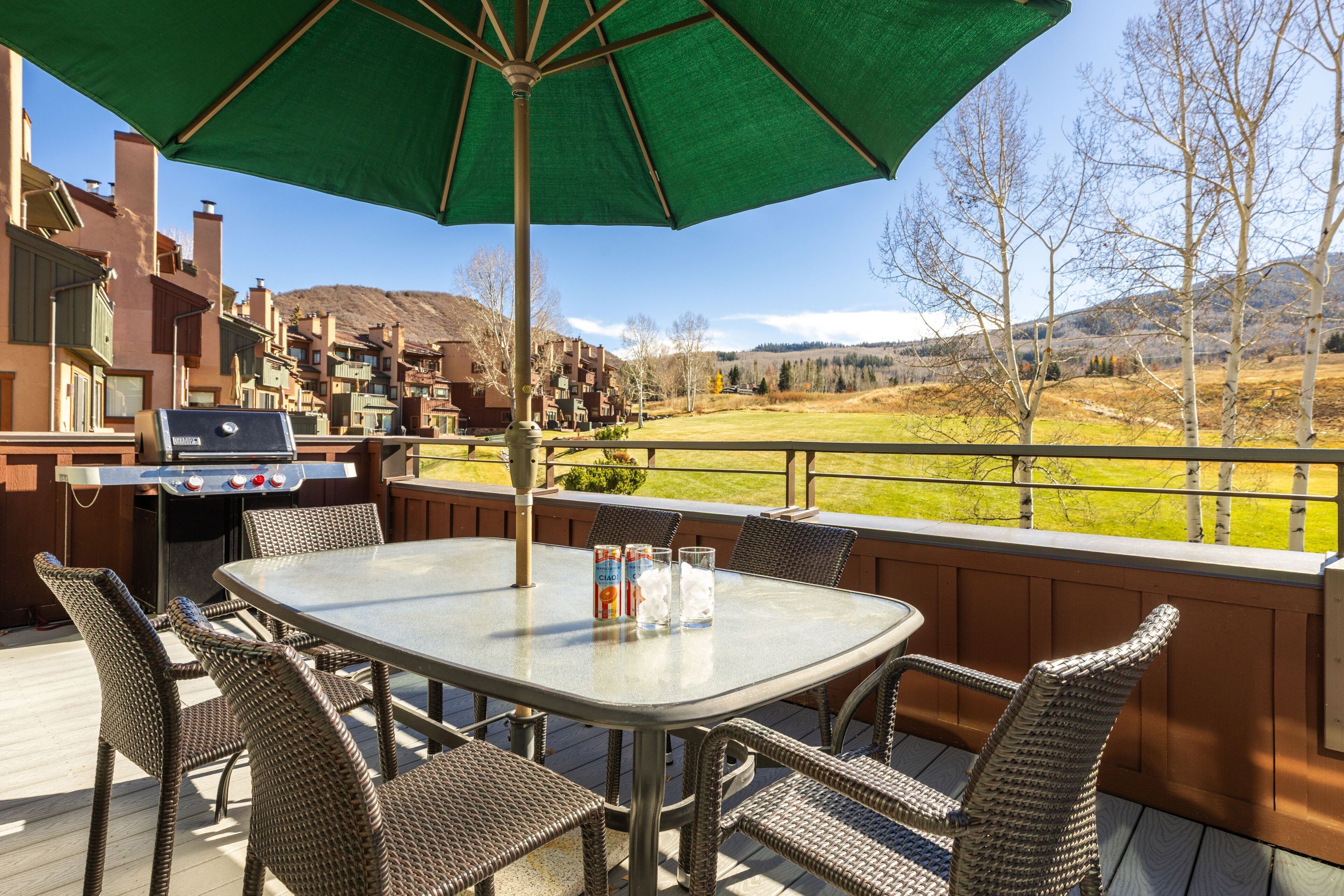 An outdoor patio with a table, chairs, and a grill.