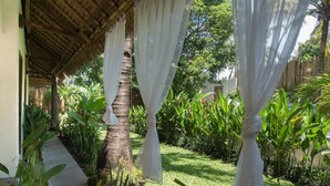 A covered outdoor area with a thatched roof, surrounded by lush greenery and a palm tree. - The Mandana Gili Air (Gili Air)