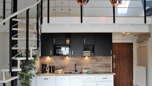 A modern kitchen with white cabinets, a brick backsplash, and a black microwave.