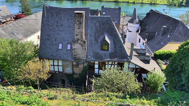 Un bâtiment traditionnel doté d’un toit en pente, entouré d’une végétation luxuriante et avec une rivière en arrière-plan.
