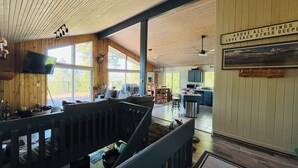 A spacious cabin with a large living area, a dining area, and a kitchen. There is a ceiling fan, a mounted television, and a sign above the kitchen. - WinterPark Chalet-3br/2ba. 2decks/hottub/mtn views. Skiing/Hiking/Biking nearby. (Tabernash)
