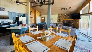 A spacious kitchen with modern appliances, a dining area with wooden tables and chairs, and a cozy living room with a stone fireplace. - WinterPark Chalet-3br/2ba. 2decks/hottub/mtn views. Skiing/Hiking/Biking nearby. (Tabernash)