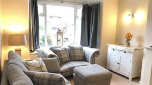 A living room with a sofa set, a lamp, a cabinet, and a window with curtains. - Charming Village house in Bramhall near Manchester (Bramhall)
