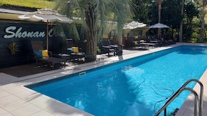 A swimming pool with lounge chairs and umbrellas, surrounded by greenery. - Shonan OVA (Yokosuka)