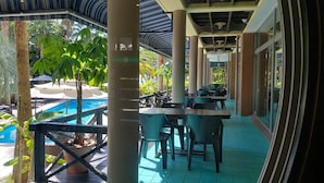 An outdoor dining area with tables and chairs, a pool, and palm trees. - Shonan OVA (Yokosuka)