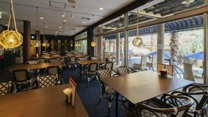 A restaurant with tables and chairs, large windows, and hanging light fixtures. - Shonan OVA (Yokosuka)