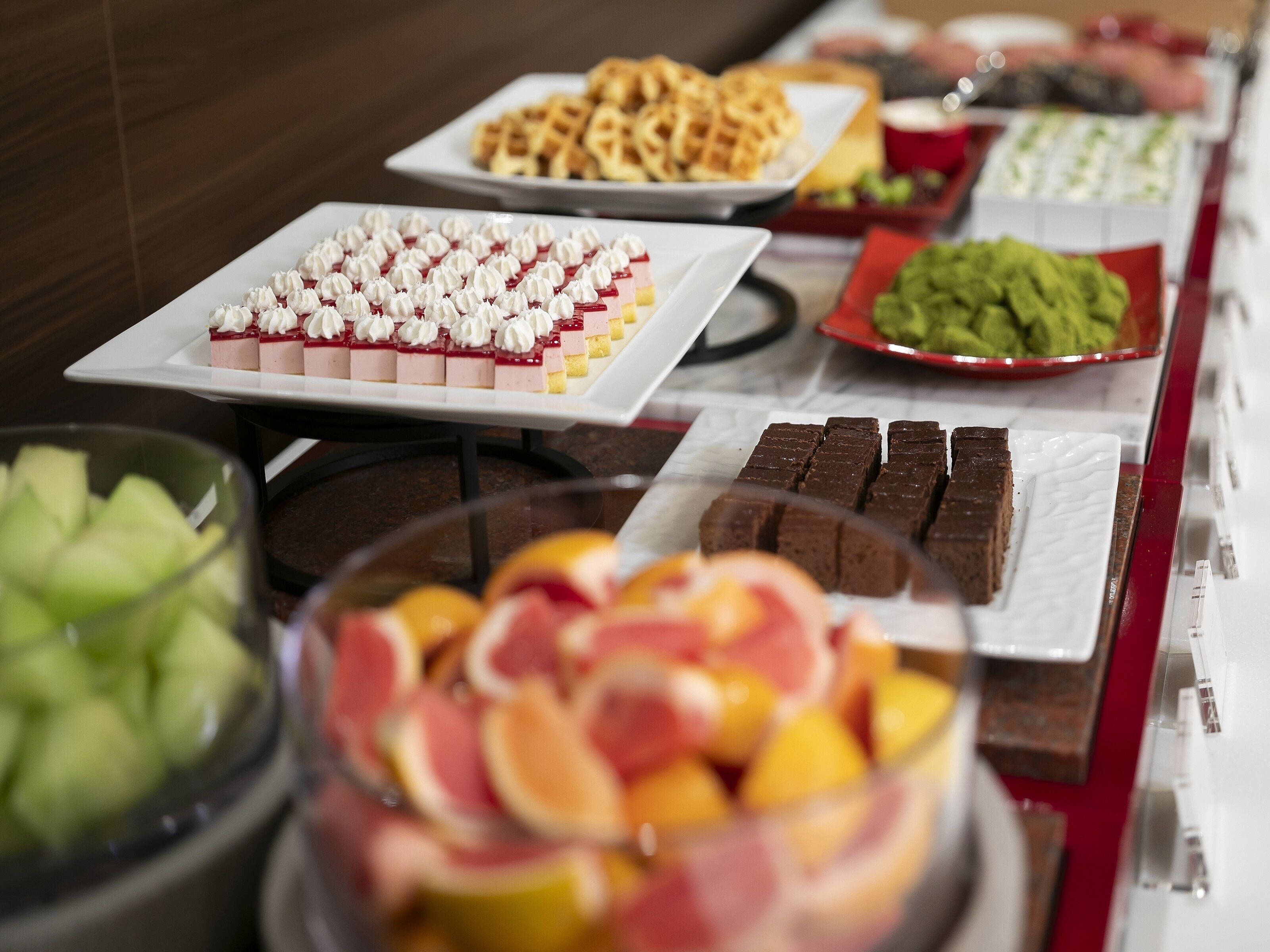 Un bufé con diversas opciones de comida, incluyendo postres, frutas y otros platos.