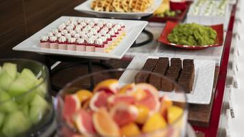 Un bufé con diversas opciones de comida, incluyendo postres, frutas y otros platos.