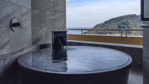 A stone bathtub with a view of a hilly landscape. - Kamenoi Hotel Atami (Atami)