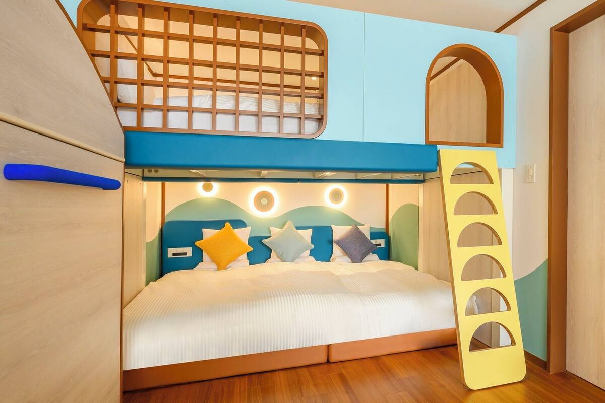 Een stapelbed met een ladder, een klein rond raam en een houten deur.