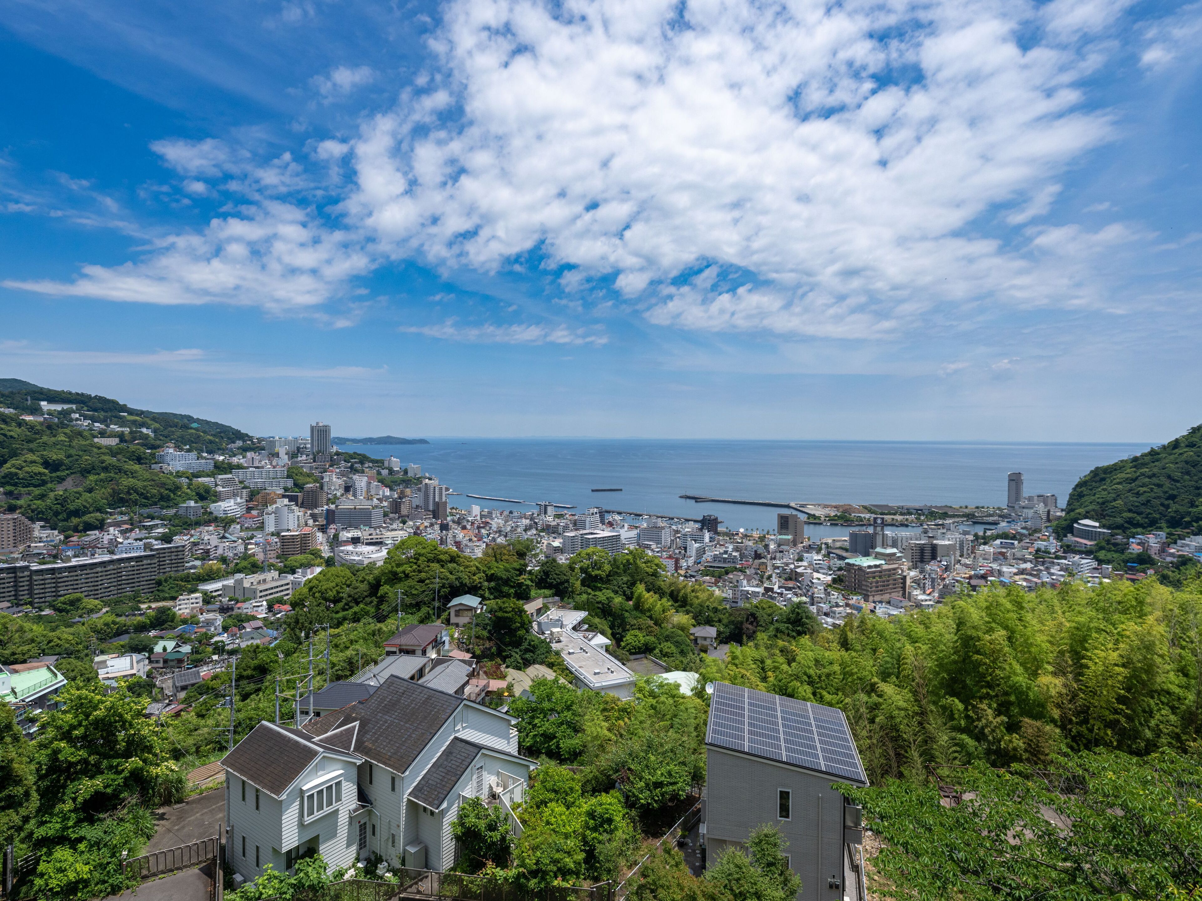 A coastal cityscape with dense urban development, a marina, and a prominent bridge.