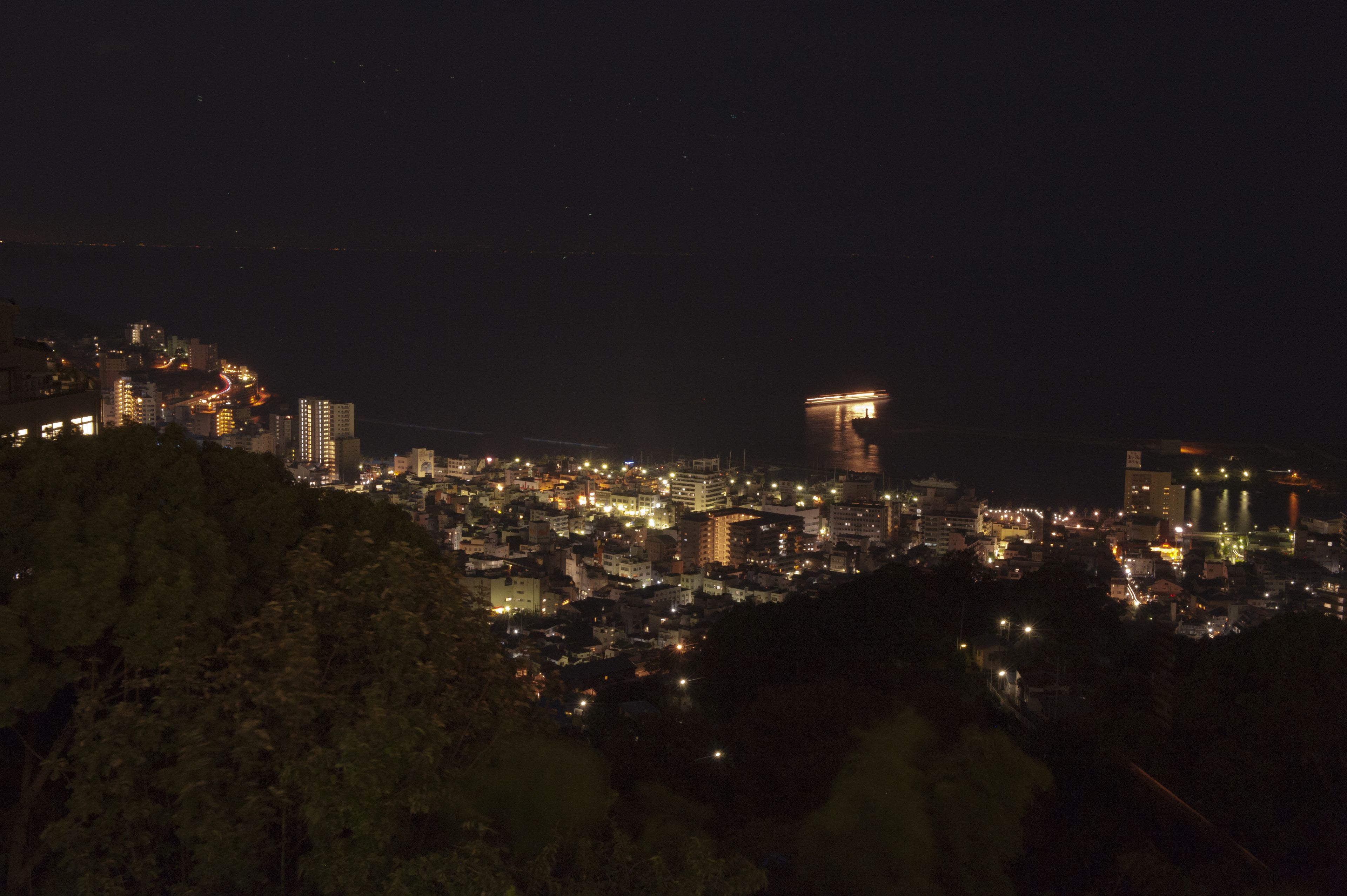 Un paisaje urbano nocturno con edificios iluminados y una torre destacada.