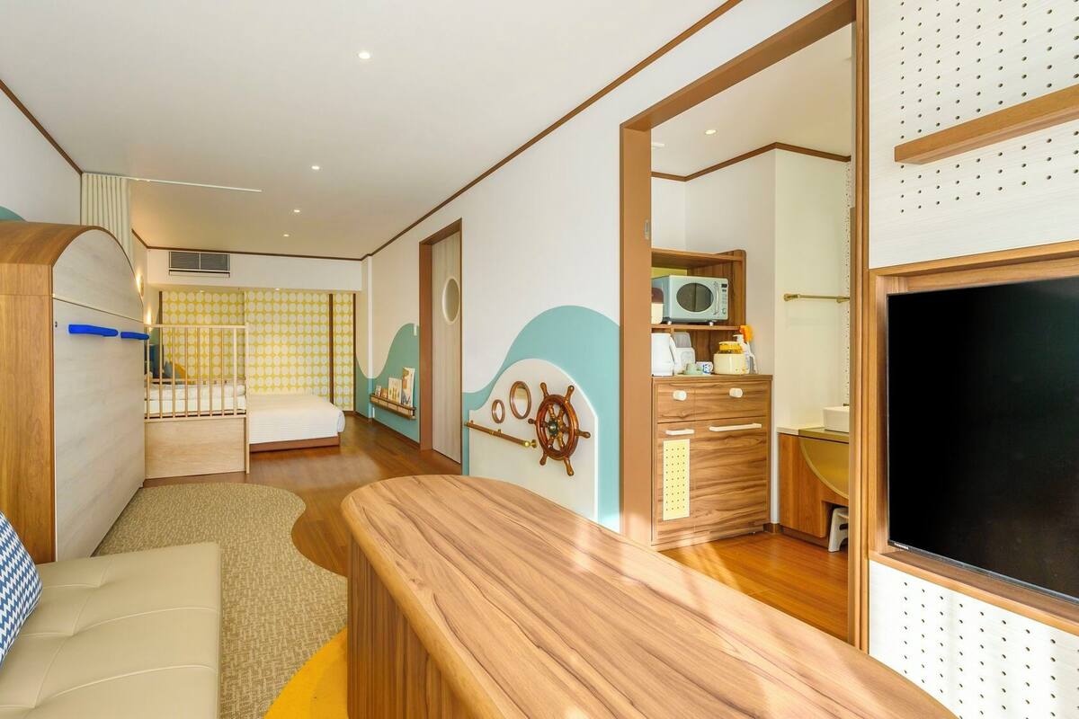 Een kleine kamer met een bed, een bureau, een stoel, een kledingkast en een televisie.
