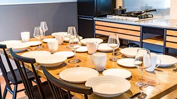 Une table à manger dressée avec des assiettes, des verres et des couverts, entourée de chaises.
