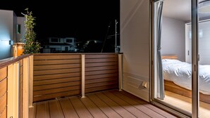 En balkon med træværksgelænder, en potteplante og udsigt til nattehimlen.