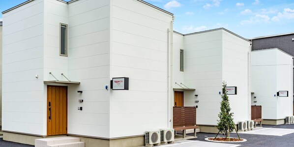A modern building with multiple units, each featuring a wooden door and a sign indicating "Rakuten Stay".