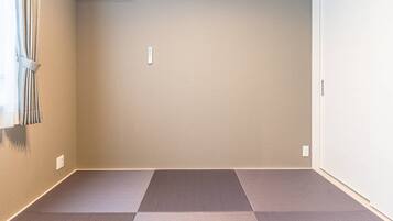 A room with beige walls, a window with curtains, and a floor with a checkered pattern.