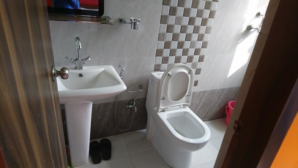 A small bathroom with a white sink, a toilet, and a tiled backsplash.
