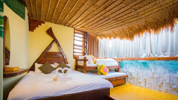 A room with a bed, a wooden headboard, a window with curtains, and a view of a pool. - Castillo Kenting (Hengchun)