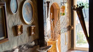 A stone-walled room with a leather sofa, framed artwork, and a vase with branches. - Castillo Kenting (Hengchun)
