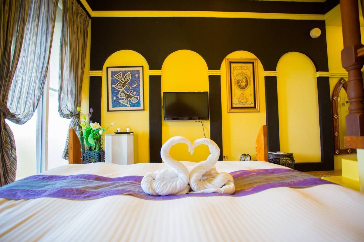 Una habitación de hotel con una cama, televisión y obras de arte en la pared.