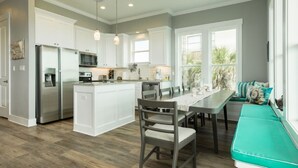 Una cocina moderna con armarios blancos, una isla central y una zona de comedor con banco.
